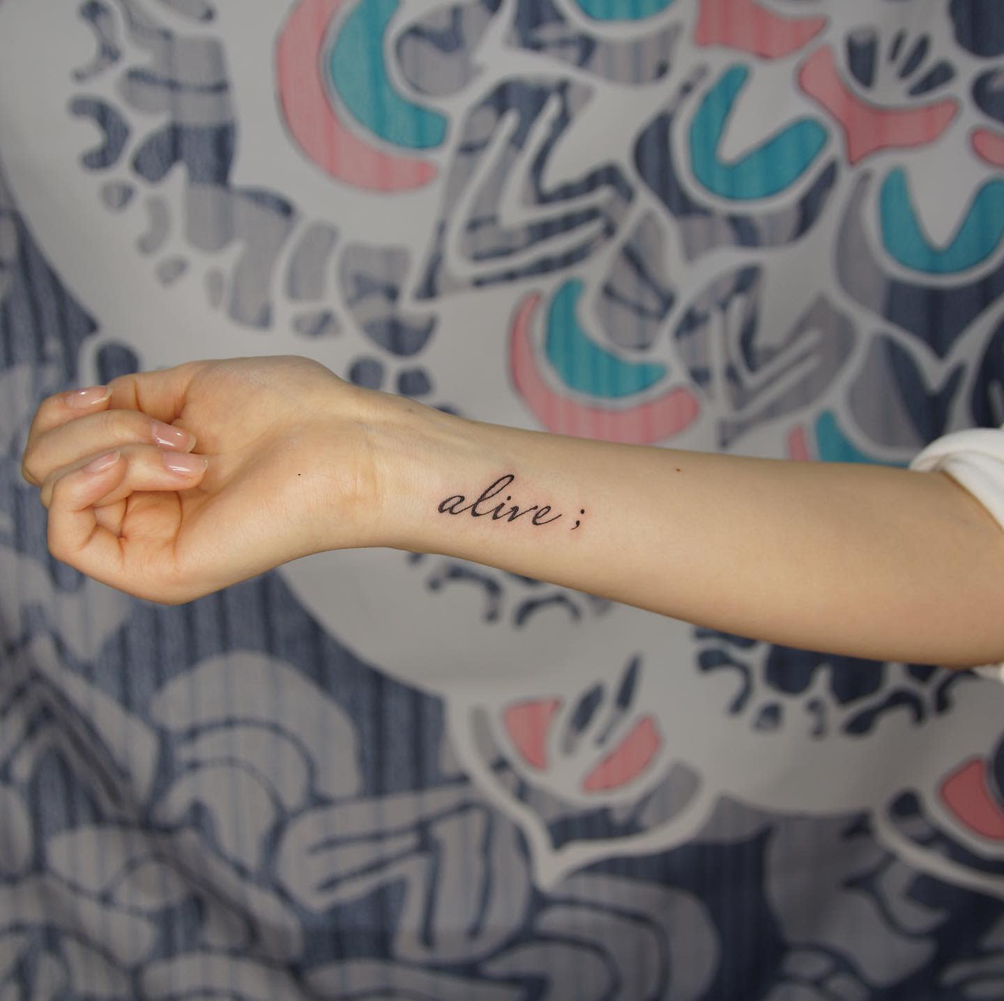 Forearm tattoo with the word "alive;"