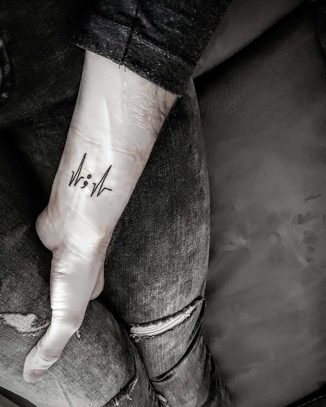 Tattoo of the semicolon with integrated heart and pulse line on a forearm