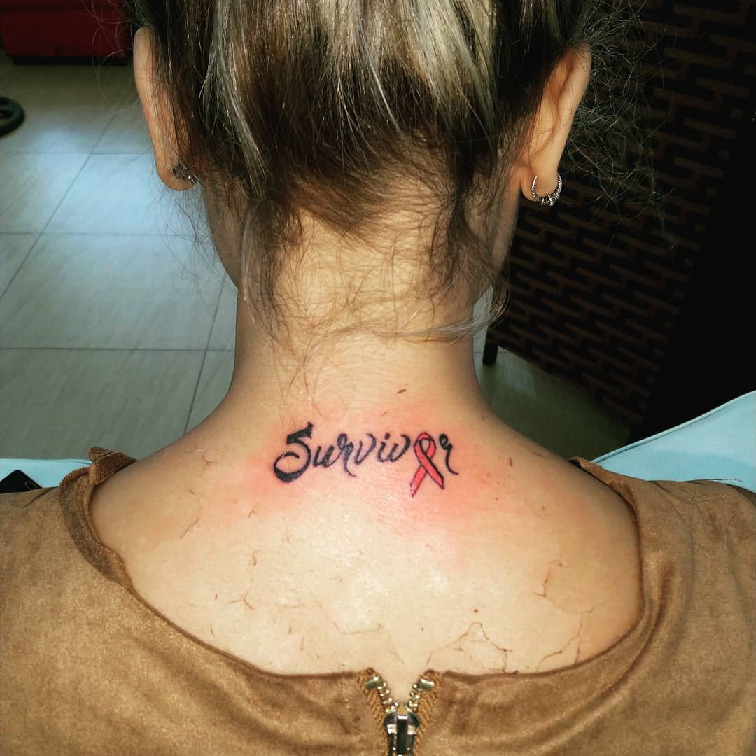 Back of neck tattoo reading "Survivor" with a pink awareness ribbon replacing the "v"