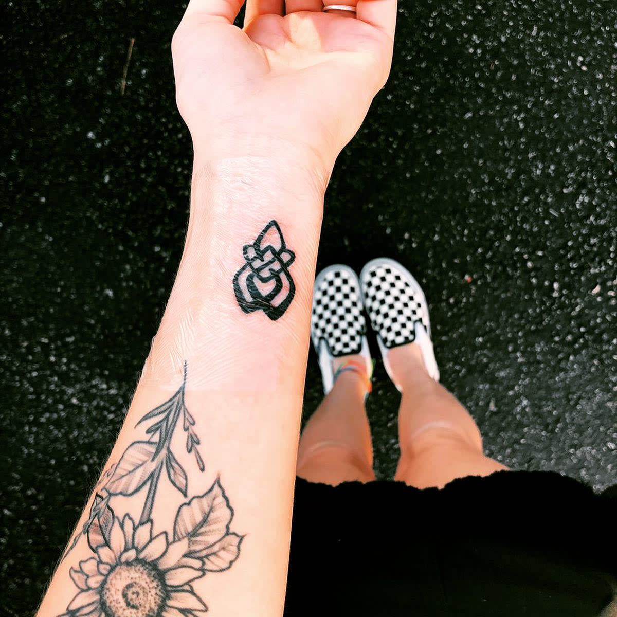 Close-up of a wrist tattoo with a geometric design and floral tattoos