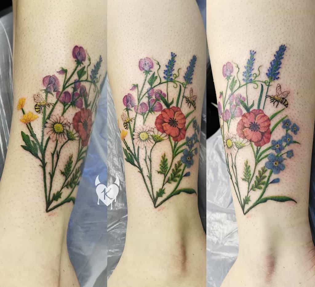 A colorful bouquet tattoo featuring sweet peas, daisies, poppies, and lavender with bees hovering nearby