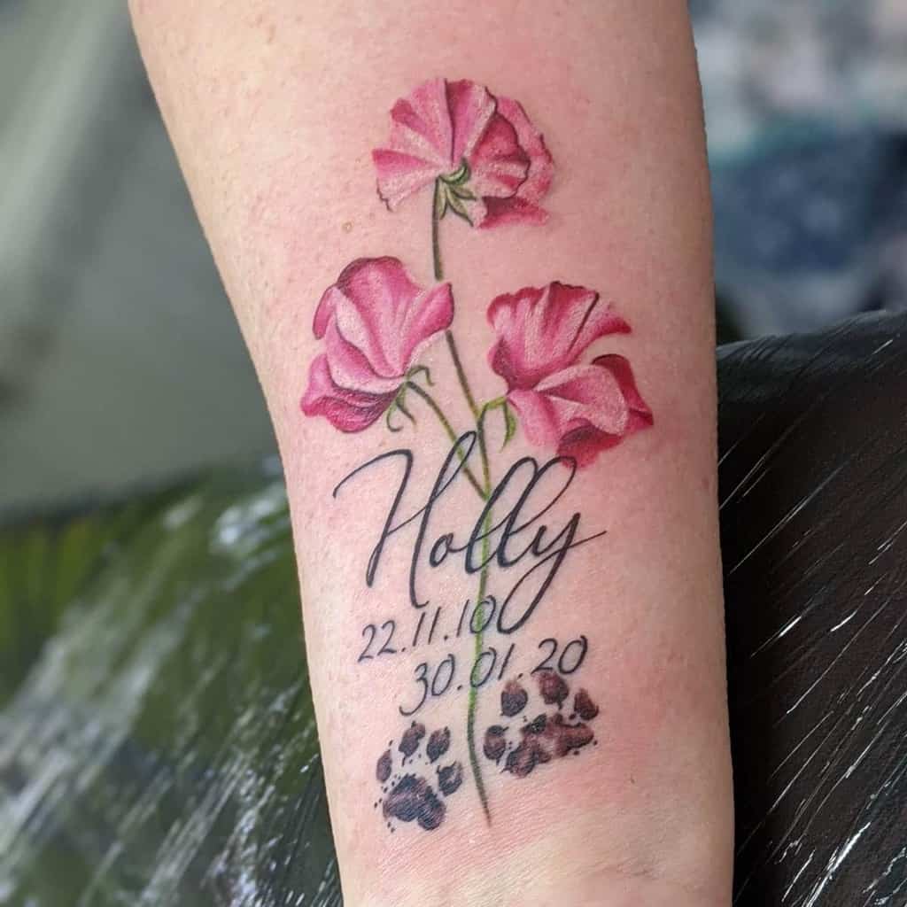 A memorial tattoo featuring pink sweet pea flowers with the name "Holly" and paw prints beneath