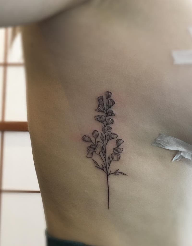 A delicate sweet pea flower tattoo with subtle shading, positioned on the ribs for a graceful, simple design