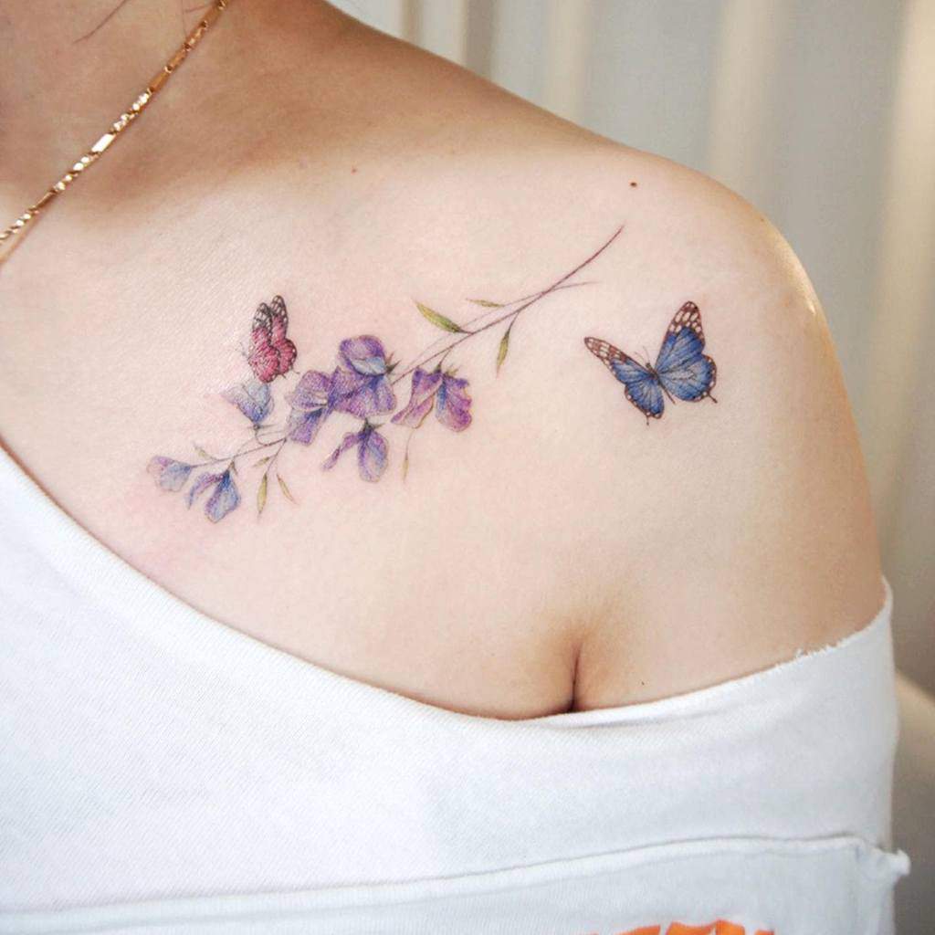 A beautiful shoulder tattoo with vibrant sweet pea blossoms and detailed butterflies, creating a whimsical and graceful design