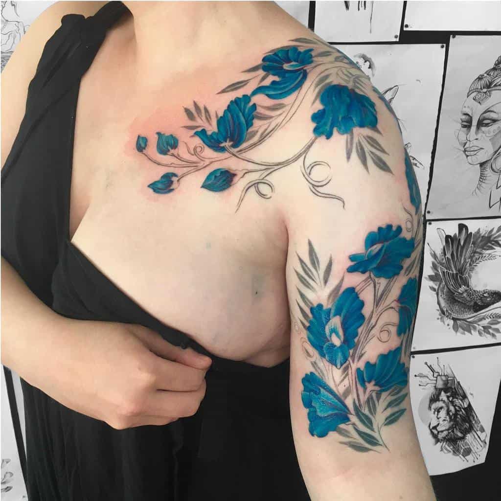 A striking floral tattoo with vivid blue sweet pea blossoms, elegantly wrapping around the shoulder and upper arm