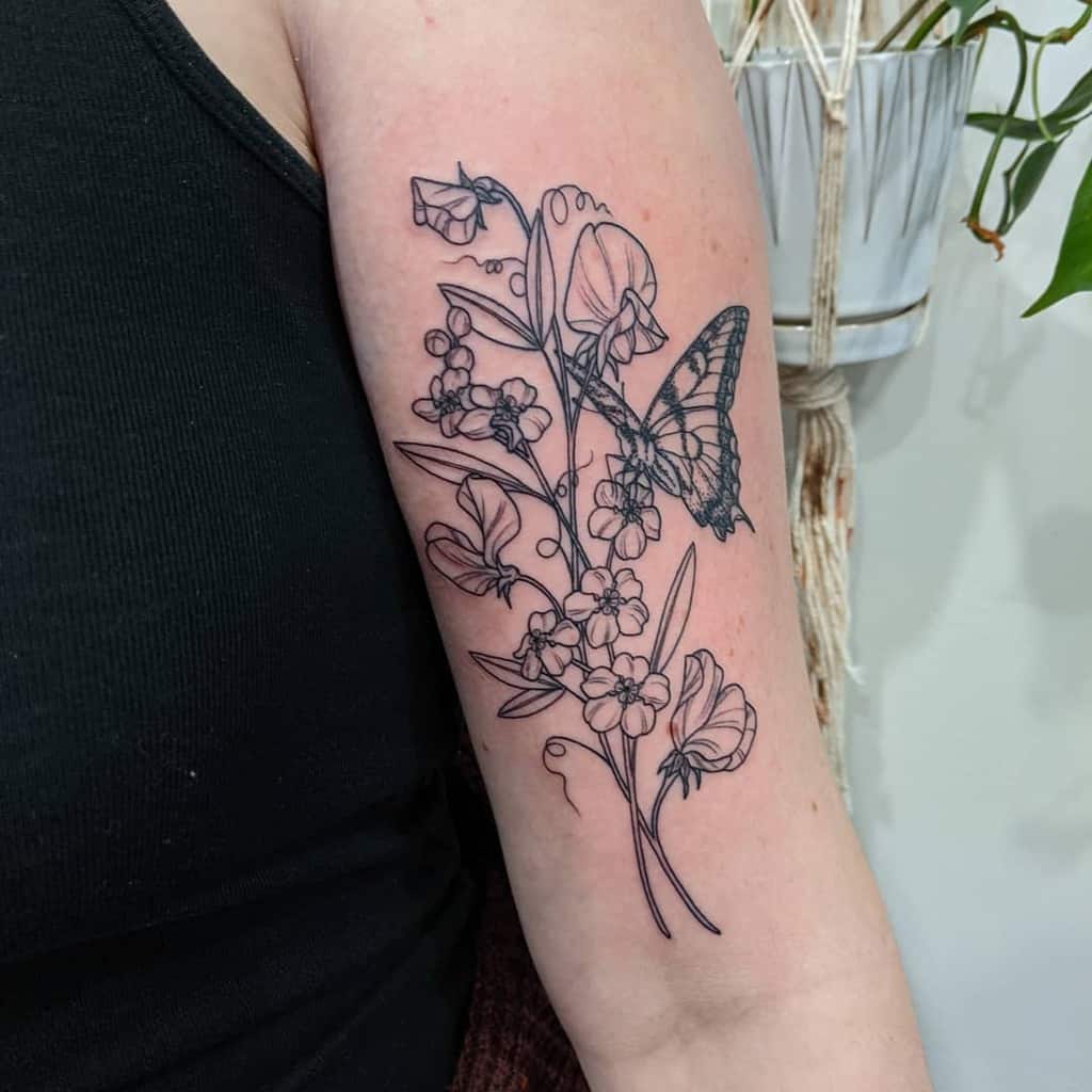 A sweet pea flower tattoo on the upper arm, featuring detailed line work and a butterfly accent