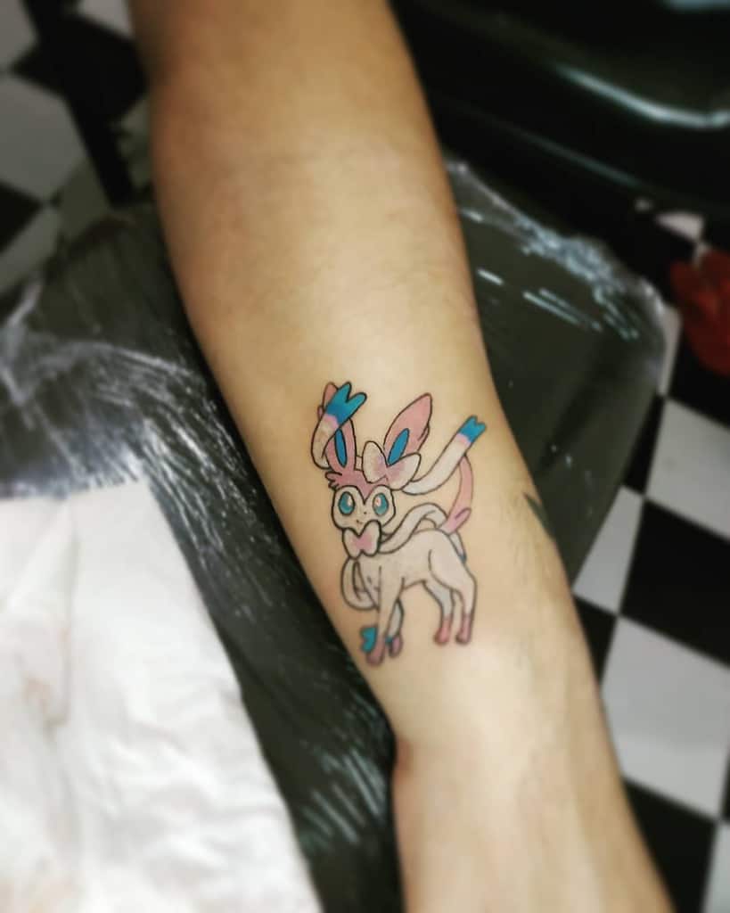 Playful Sylveon tattoo with pastel pink and blue accents, showcasing its signature ribbons and cheerful expression