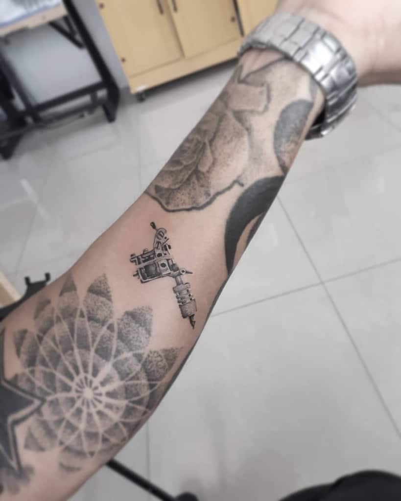 Detailed single needle tattoo of line art flowers and a small spacecraft on an arm wearing a metal watch