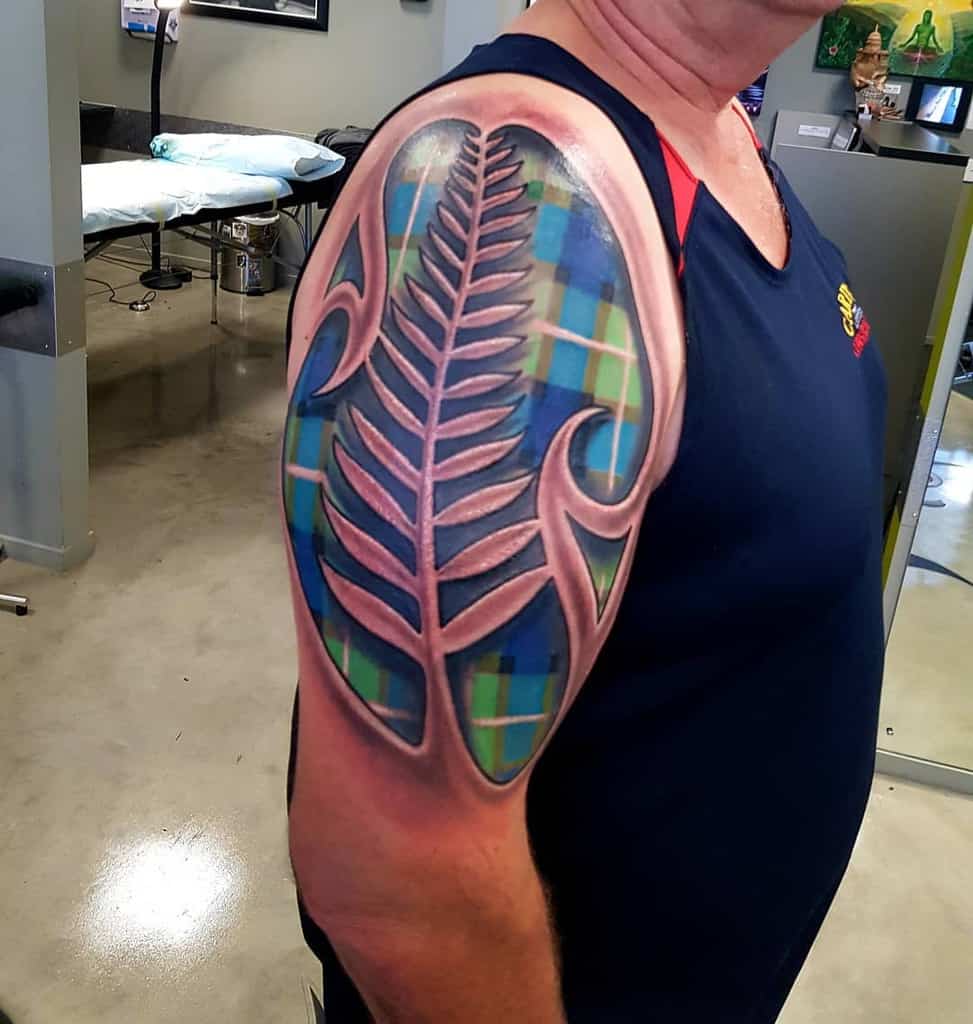 Colorful tattoo featuring a Scottish thistle with a tartan background in blue and green hues