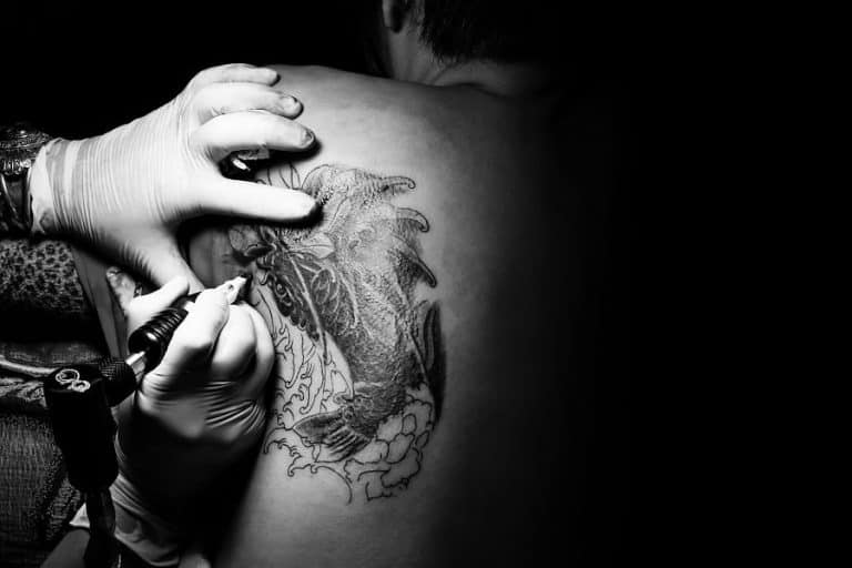 Tattoo artist tattooing back