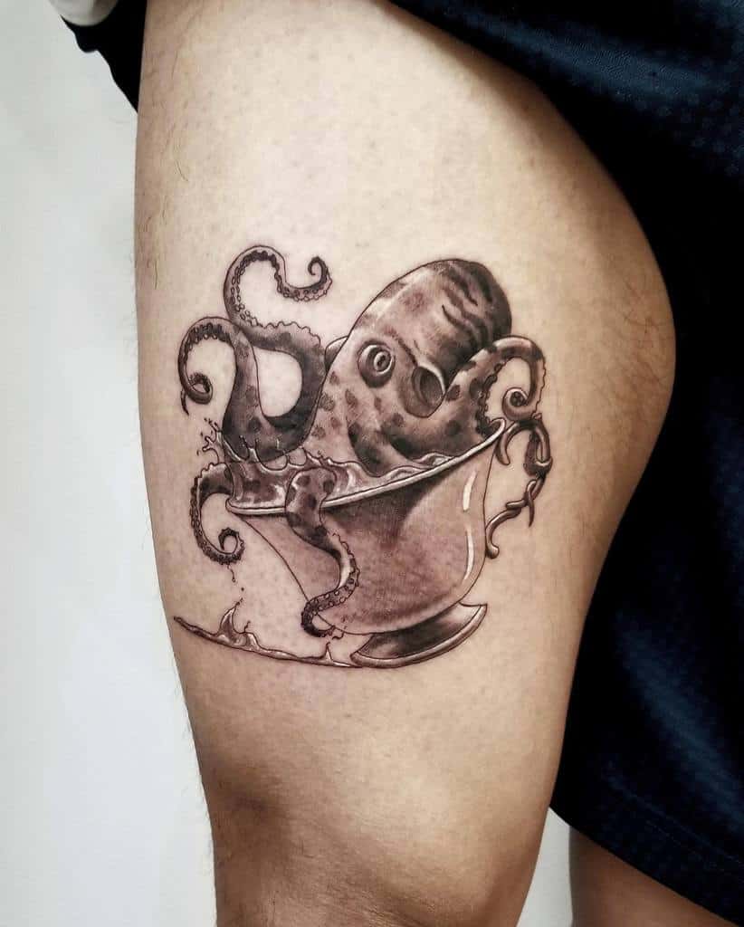 Black and grey tattoo of an octopus emerging from a teacup, with detailed shading and tentacles spilling over the edge, creating a surreal design
