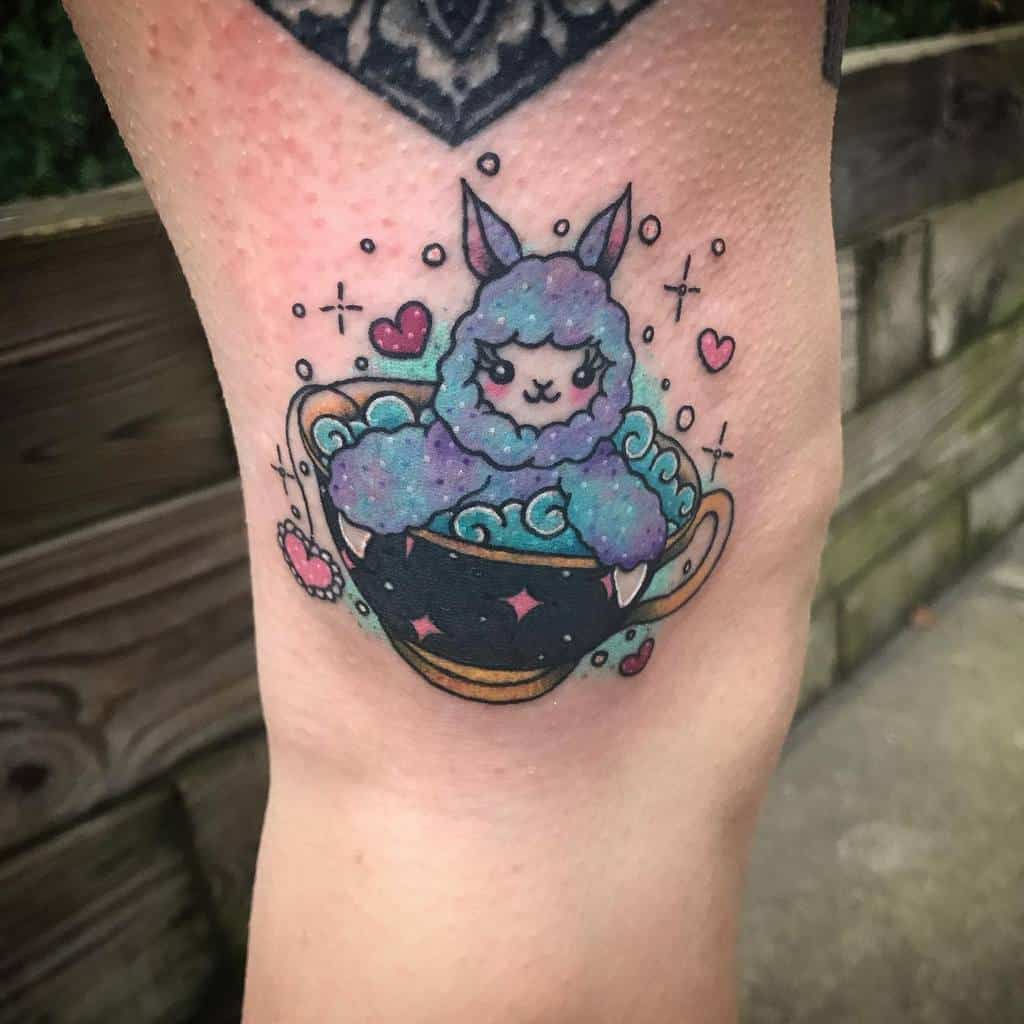 Cute and colorful tattoo of a fluffy alpaca taking a bath in a black teacup with golden details and pink diamond-like star designs, surrounded by bubbles, hearts, and sparkles