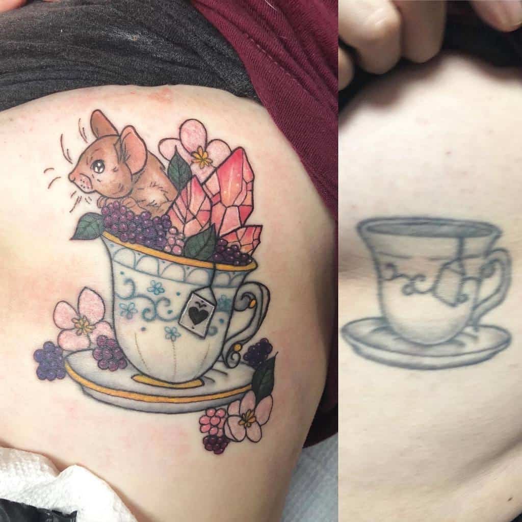 Before-and-after tattoo comparison; the original black teacup tattoo is transformed into a colorful design featuring a teacup with blue floral patterns, a mouse, pink crystals, berries, flowers, and a tea bag tag with a heart, all resting on a saucer