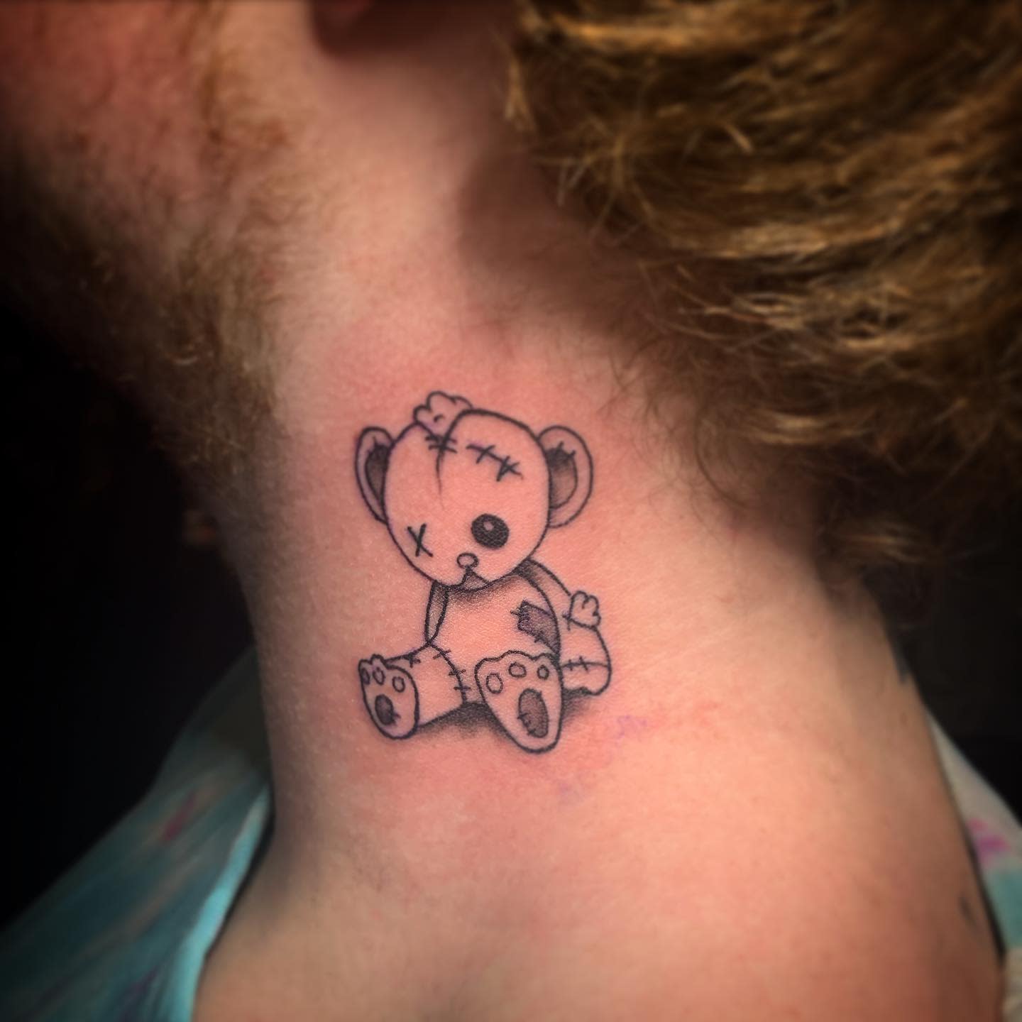 A tattered teddy bear tattoo on the neck