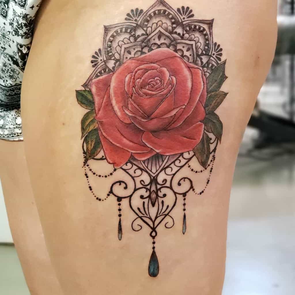 Chandelier-style tattoo featuring a realistic red rose, intricate mandala details, ornamental swirls, and teardrop-shaped crystal accents