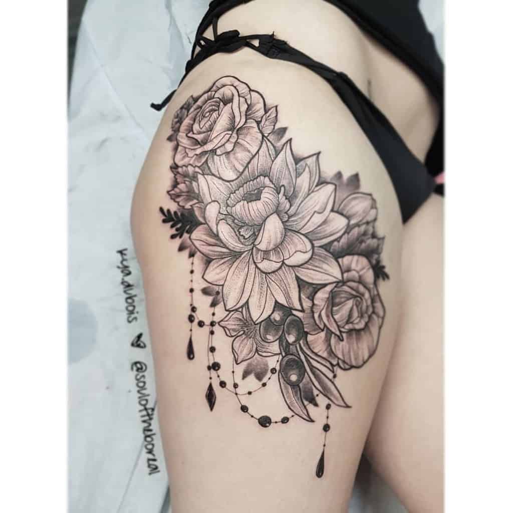 Chandelier-style tattoo featuring detailed black and grey roses, lotus flowers, hanging beads, teardrop crystals, and ornamental accents