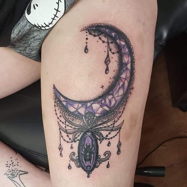 Chandelier-style crescent moon tattoo with purple gemstone details, beaded chains, diamond-shaped crystals, and an ornate gothic oval pendant with spider on it