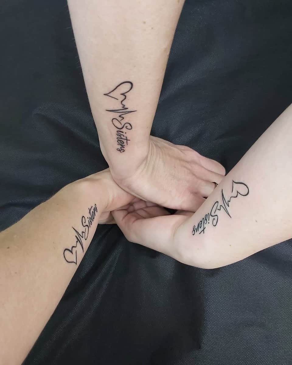 Three arms with matching heart tattoos and "Sisters" text, joined in the center