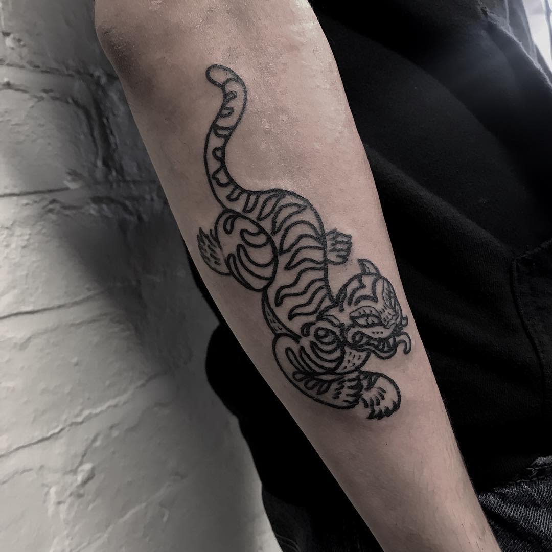 Forearm tattoo of a stylized tiger with curved lines and patterns on an arm