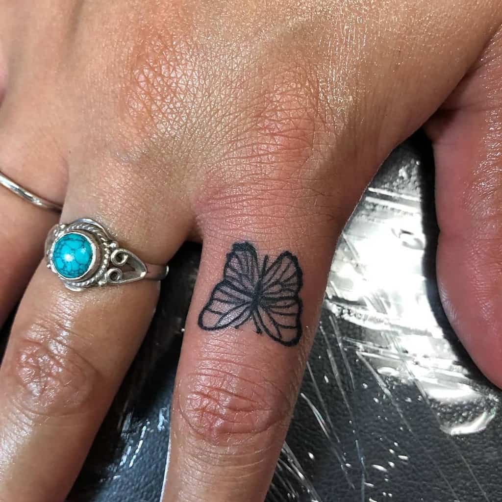 A black butterfly tattoo graces one finger