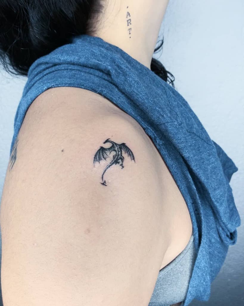 Small dragon tattoo on a person's upper arm