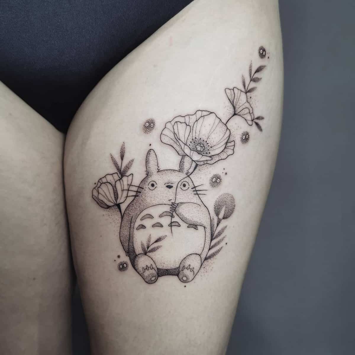 Delicate black and grey Totoro tattoo  surrounded by flowers and leaves