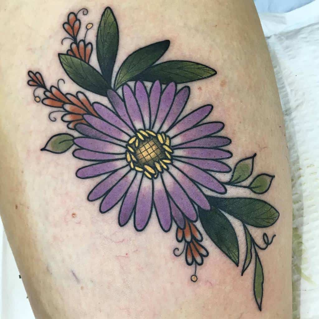 A tattoo of a purple aster with green leaves and small orange buds
