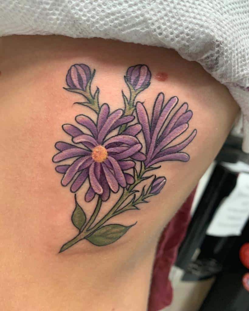 Tattoo of purple aster flowers and green leaves on the side of a person's torso