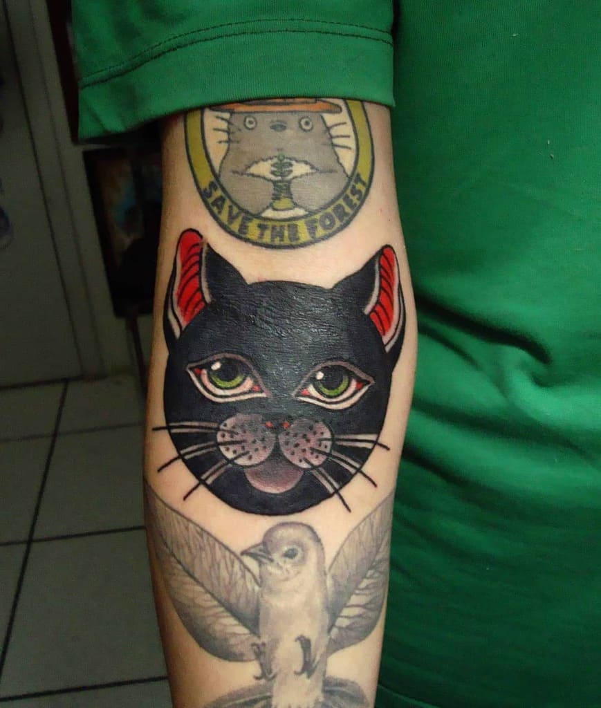 Forearm tattoos: a black cat head and a bird in flight