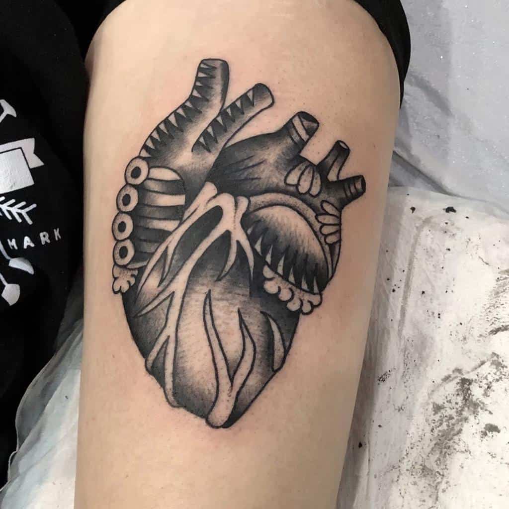Detailed black and grey anatomical heart tattoo with bold shading and intricate linework