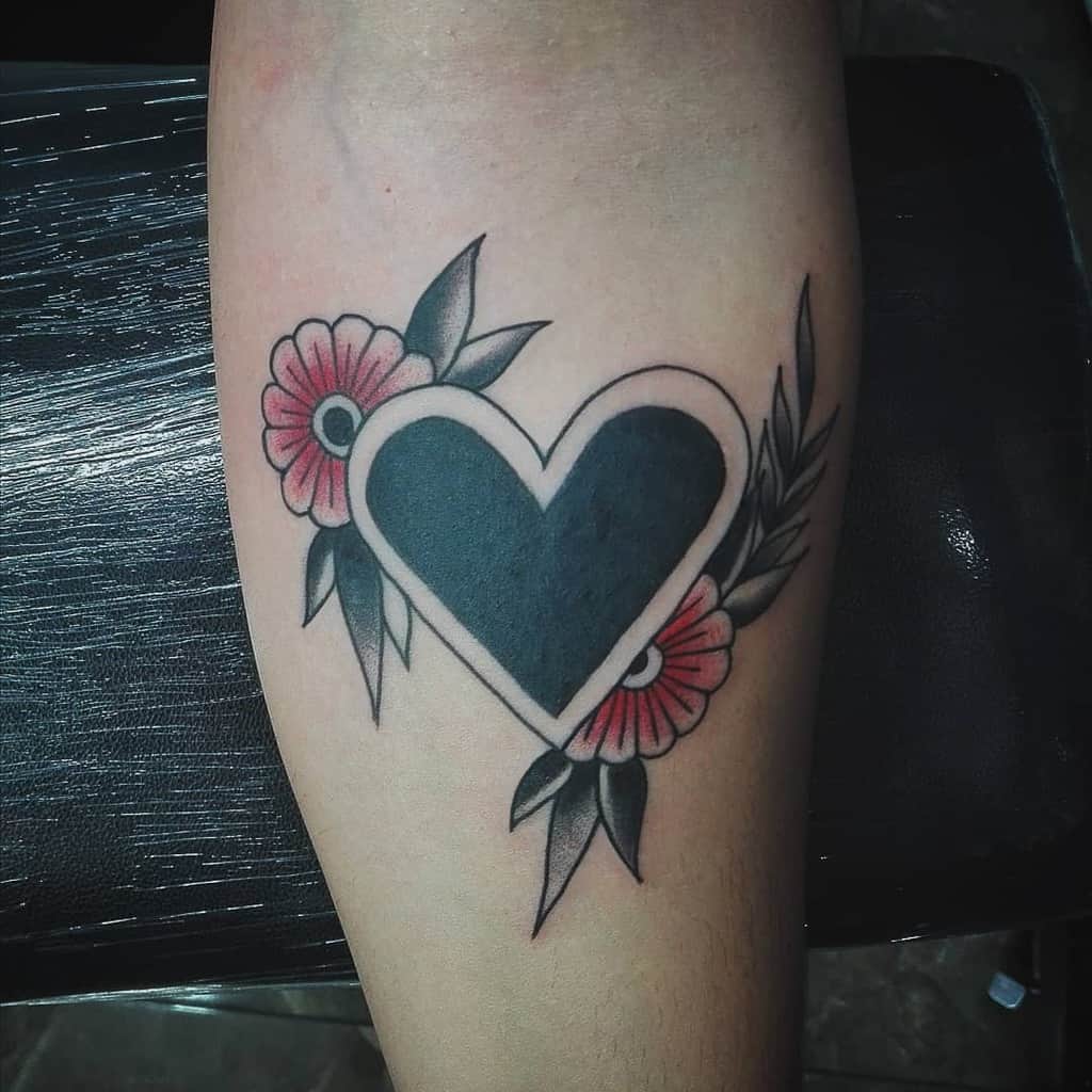 Bold black heart tattoo with a white border, surrounded by red flowers and leafy details