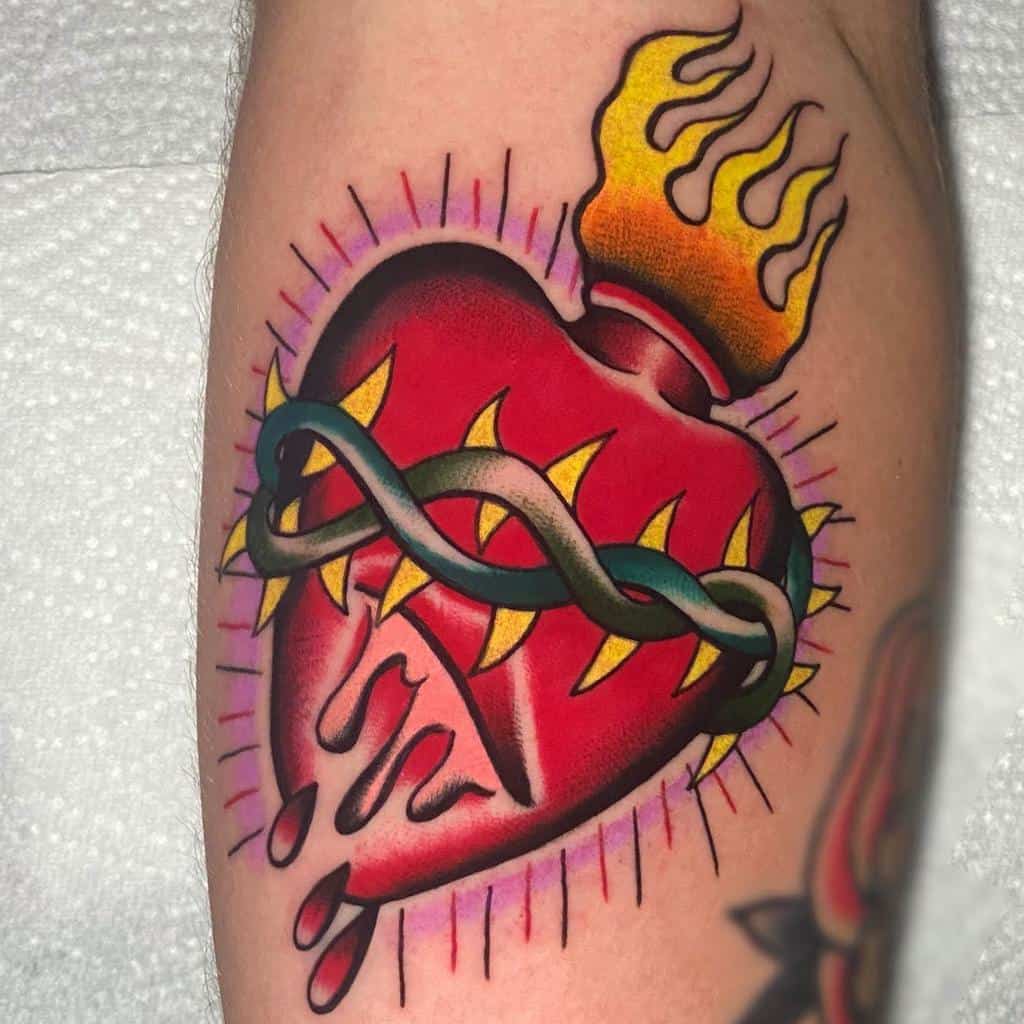 Tattoo of a bleeding, flaming heart with thorns and a wrapped snake on an arm