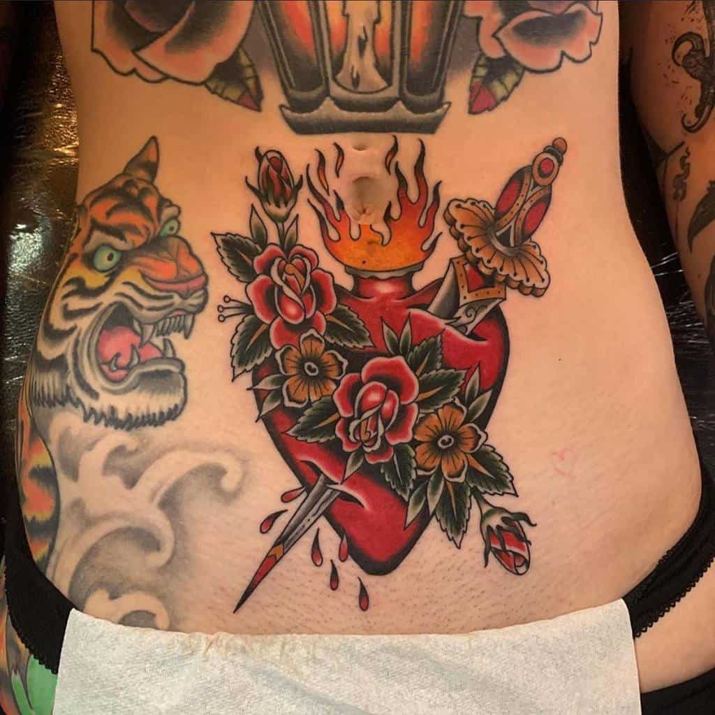 Tattooed back with a flaming heart, flowers, and a dagger through it, beside a tiger head