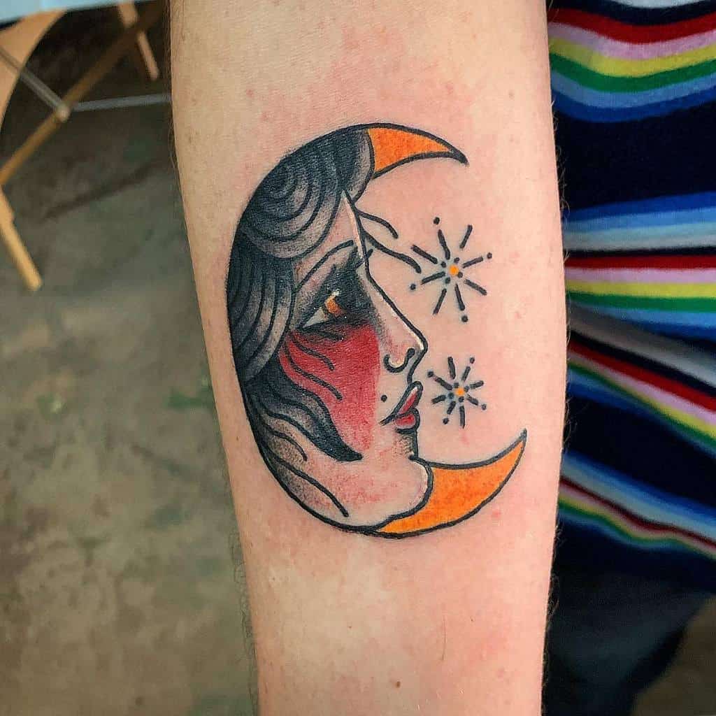 Tattoo of a crescent moon with a face surrounded by sparkling stars on a person's arm