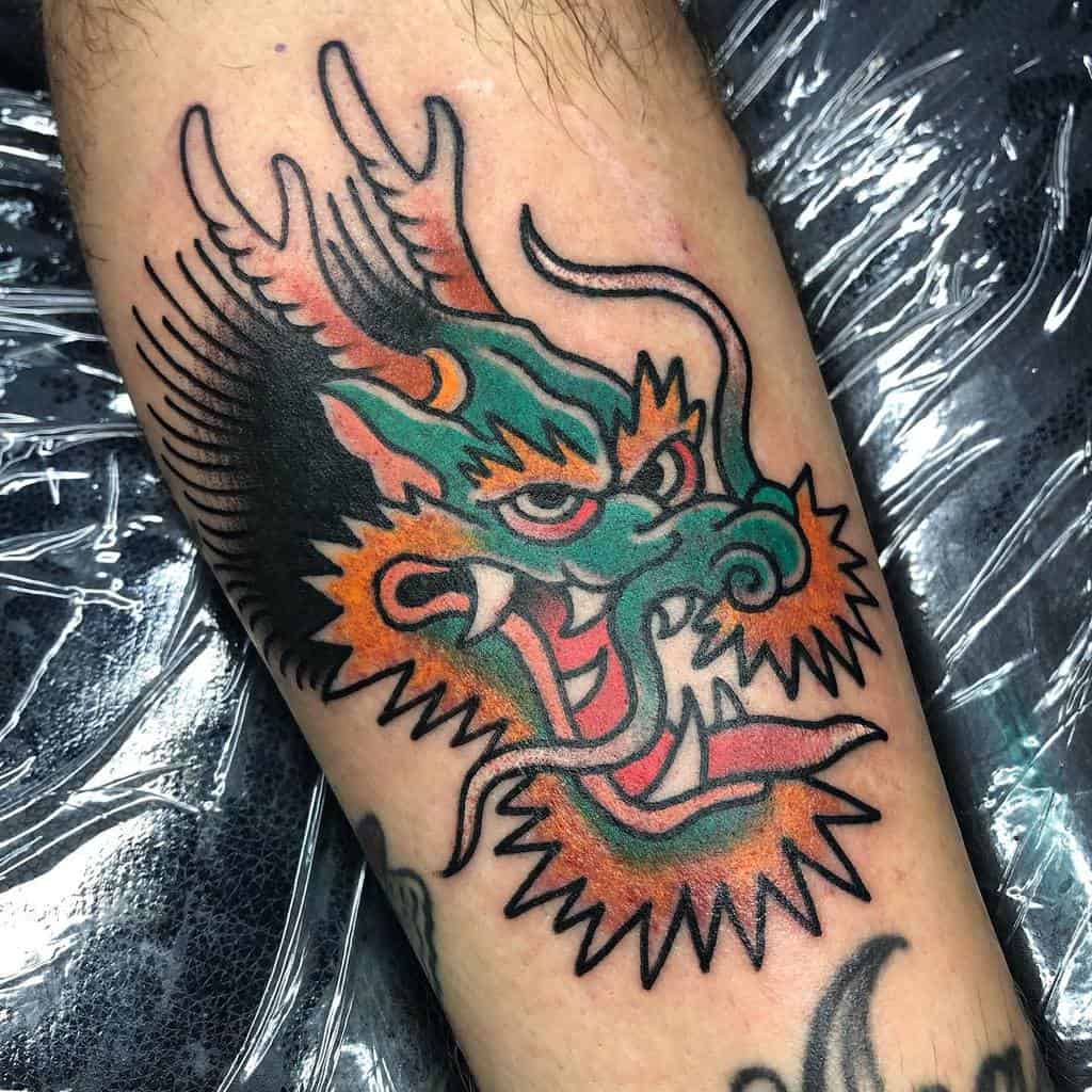 A traditional dragon head tattoo, complete with menacing horns and sharp teeth, graces the arm
