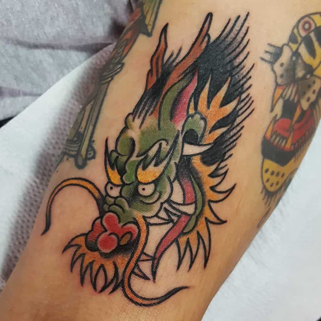 A traditional dragon tattoo, showcasing a fierce head surrounded by dynamic flames, adorns the skin