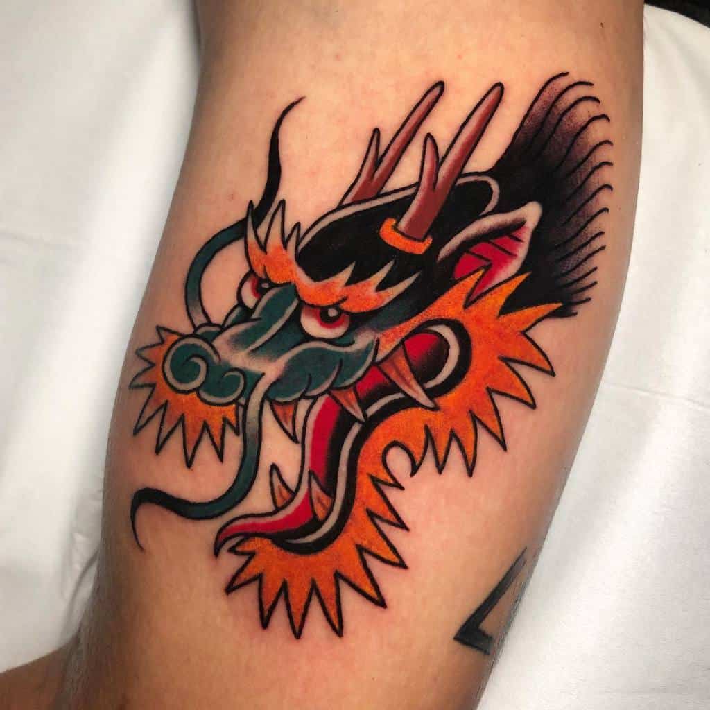 Traditional tattoo of a vibrant, colorful dragon's head with striking orange, black, and teal details on an arm