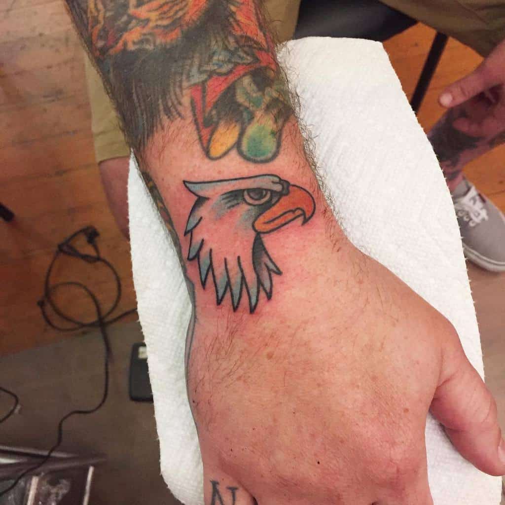 Close-up of a tattooed hand with a vibrant eagle head tattoo on the wrist