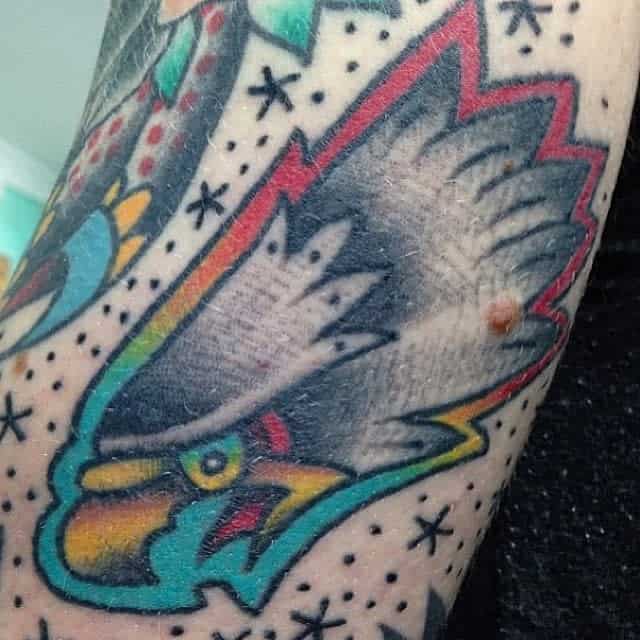 Close-up of colorful tattoo on arm depicting an eagle's head with star decorations around it