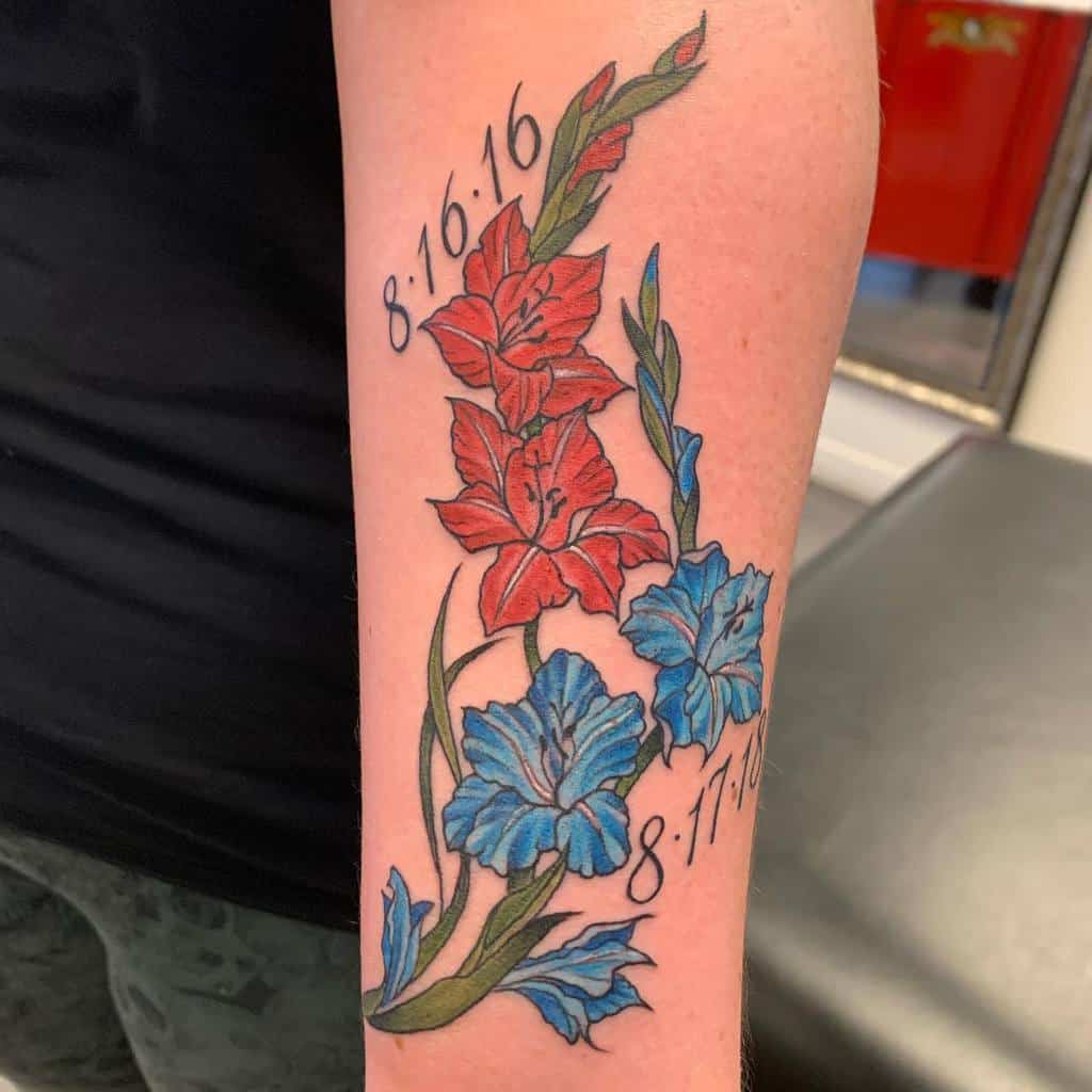 Tattoo of vibrant red and blue gladiolus flowers with the dates 8-16-16 and 8-17-16 on a person's forearm