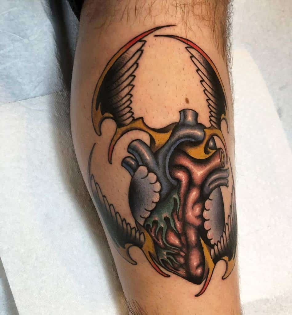Tattoo of an anatomically correct heart with graceful wings on a person's forearm