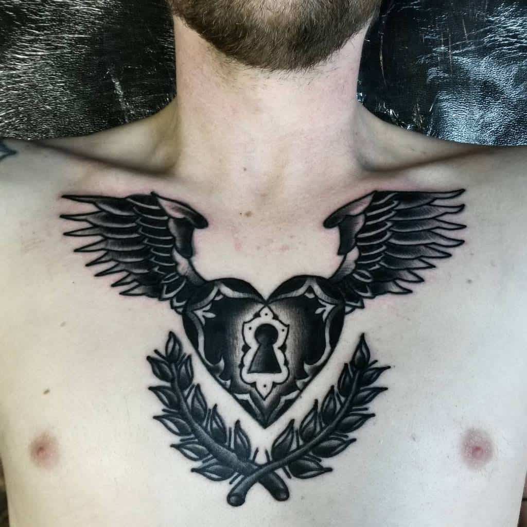Chest tattoo featuring wings, a keyhole, heart, and laurel leaves elegantly etched on the person's upper chest