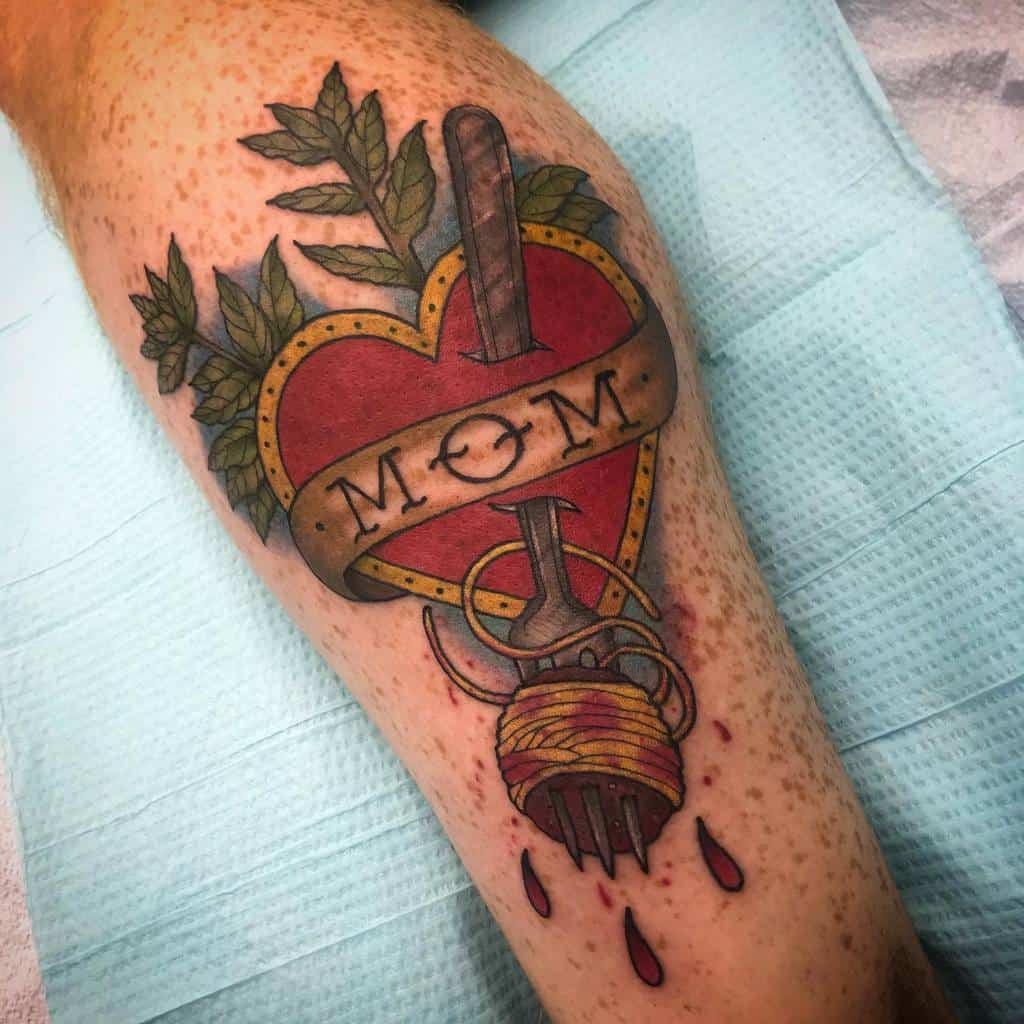 Traditional tattoo of a red heart with a 'MOM' banner, a dagger, leaves, and a fork stabbing a meatballs wrapped by noodles, dripping blood