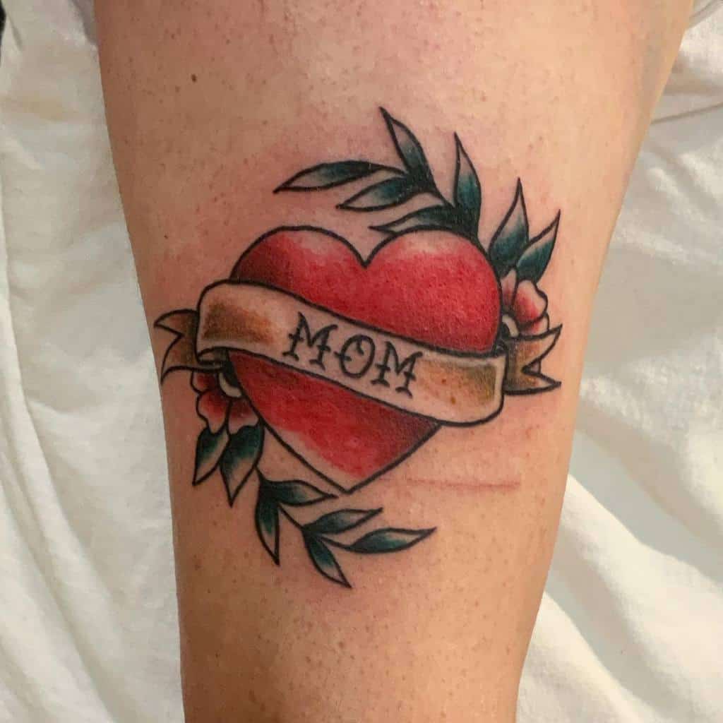 A vibrant tattoo features a red heart with a "MOM" banner, adorned beautifully with flowers and leaves