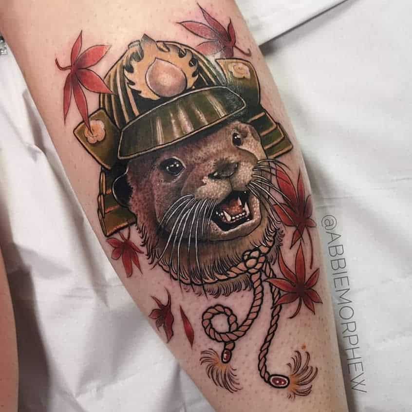 Tattoo of an otter in a samurai helmet, surrounded by red leaves and intricate rope detail