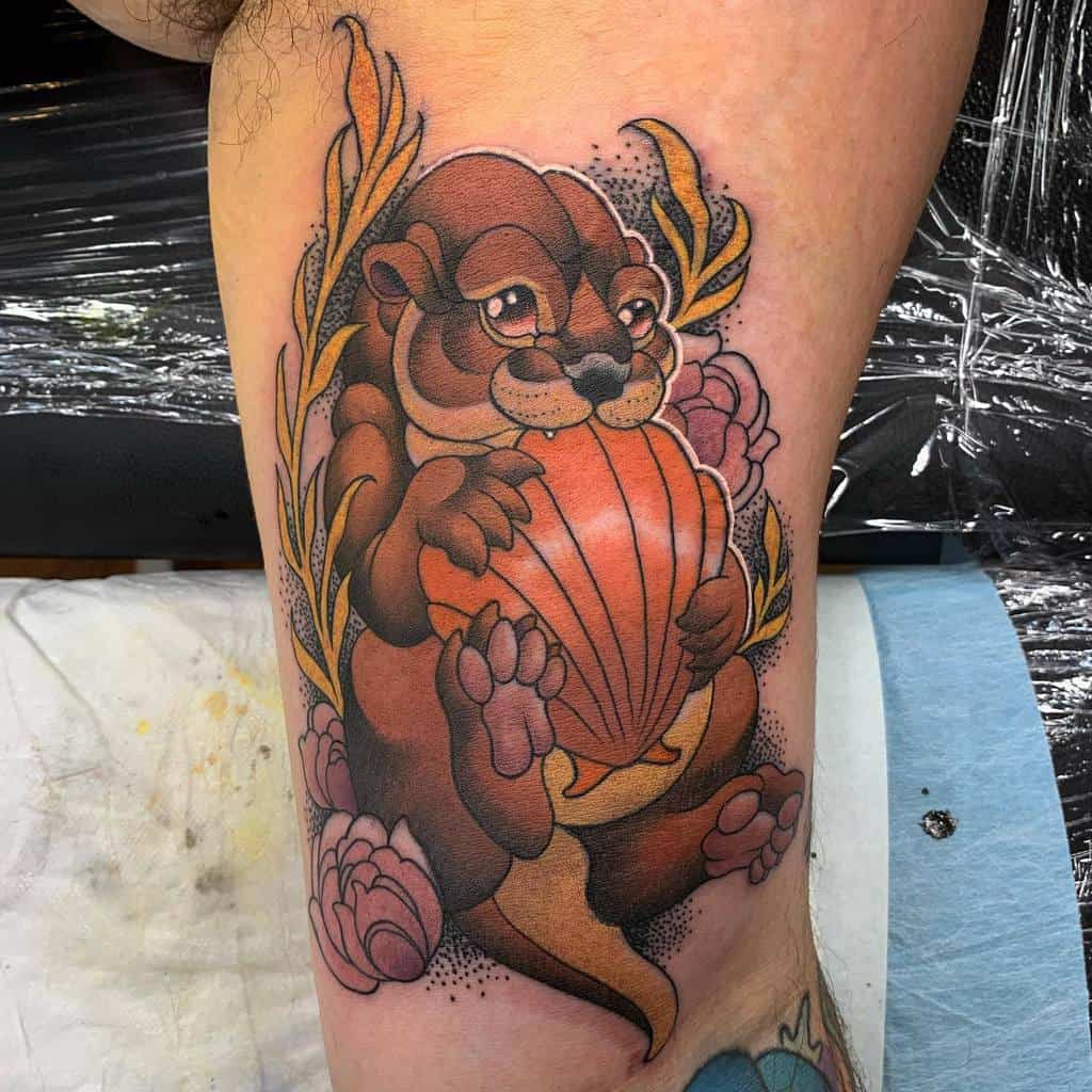 Tattoo of a cartoon otter holding a shell, surrounded by flowers and leaves