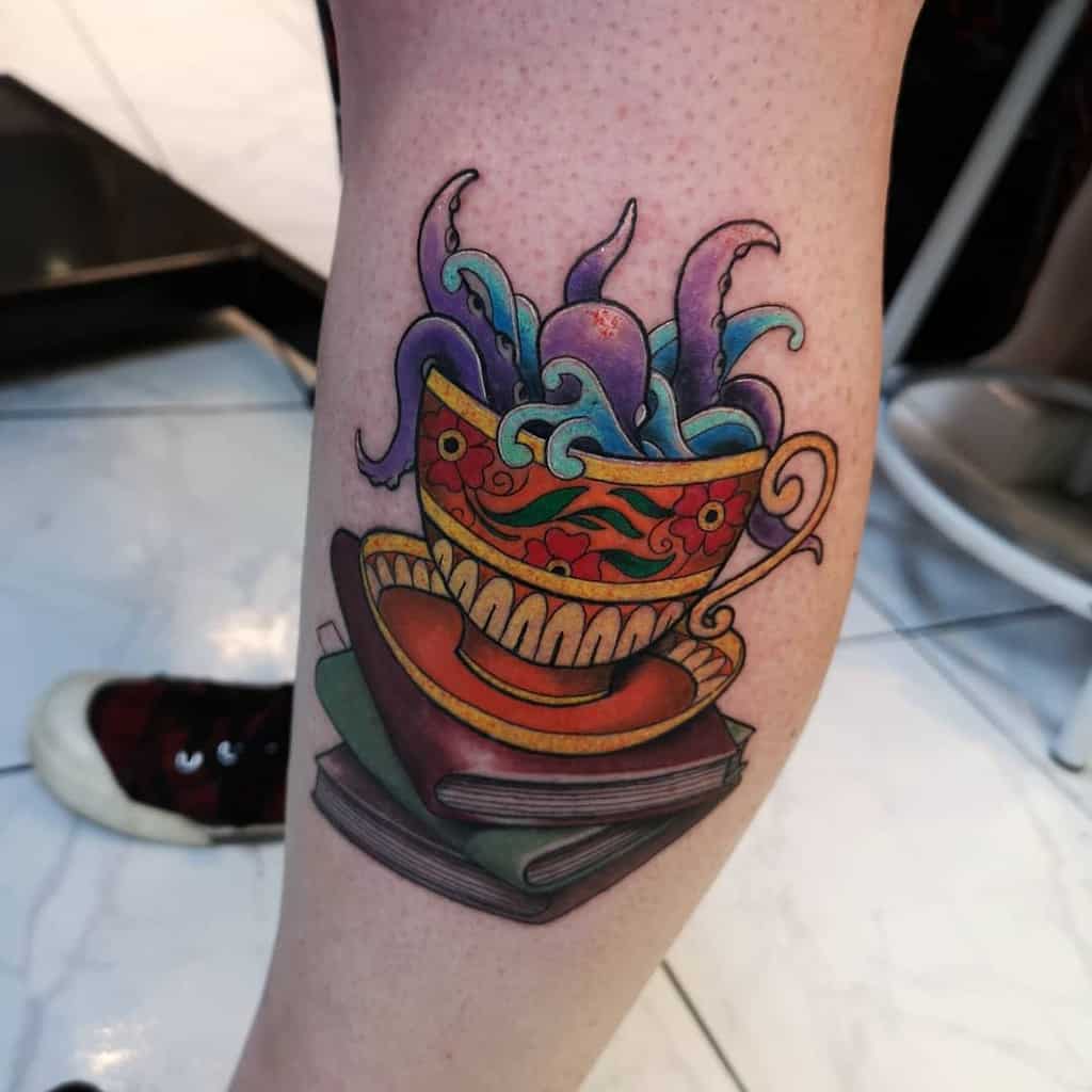 Colorful tattoo of a floral teacup with swirling tentacles of octopus emerging from it, resting on a matching saucer and three stack of books for a mystical theme