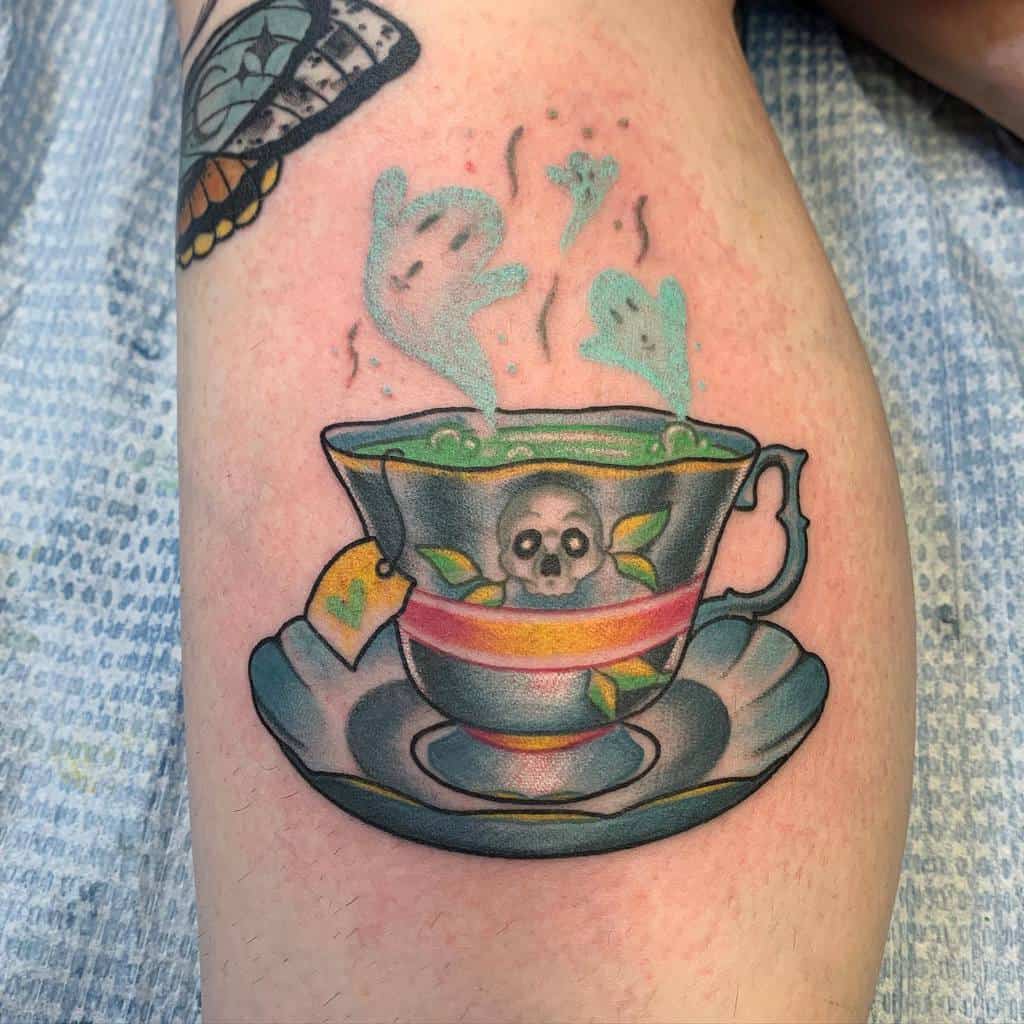 Colorful tattoo of a teacup with a skull and leaf design, steam forming ghost shapes from bubbling green liquid, tea bag with a heart, resting on a matching saucer