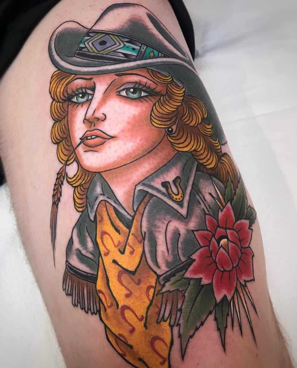 Tattoo of a cowgirl with a hat and feather, colorful clothing, and a flower on the arm