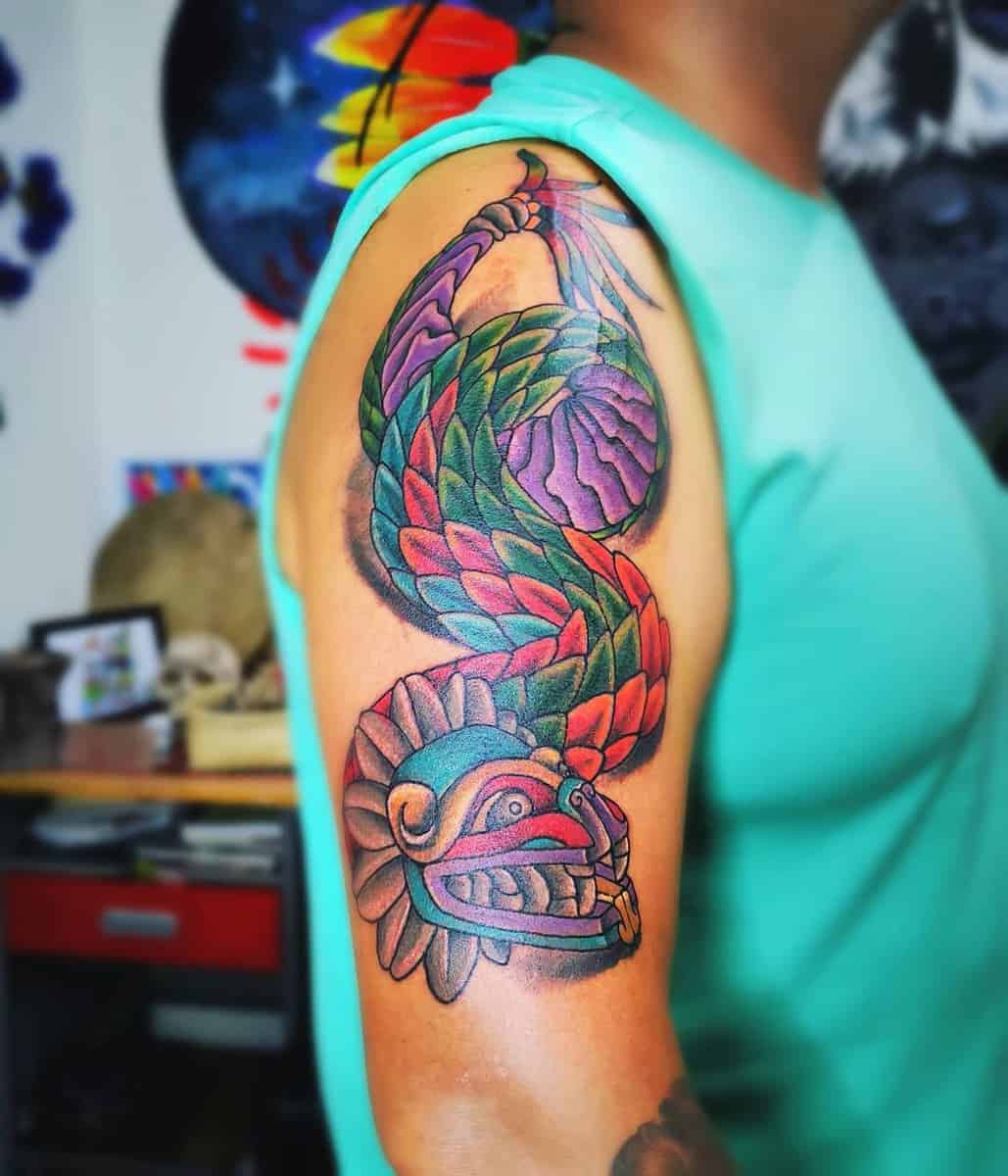 Colorful upper arm tattoo of Quetzalcoatl with vibrant feathered serpent design.